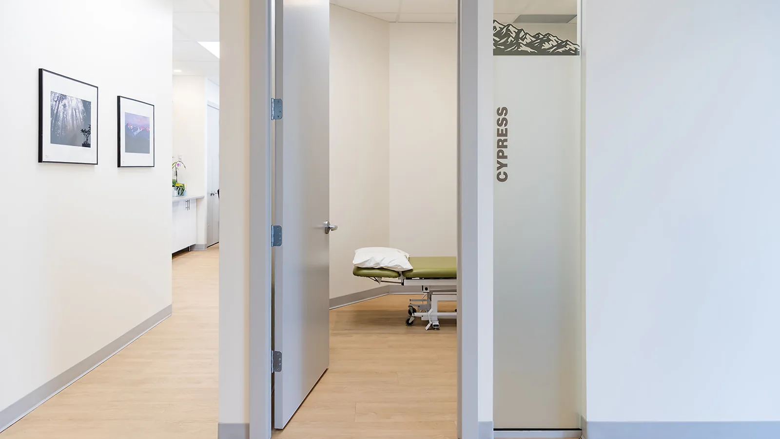 A calm clinic hallway with an open door to a treatment room and a massage table
